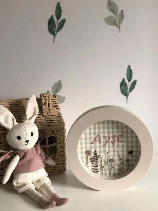A bunny on a dresser in front of a wall decorated with leaf wall decals.