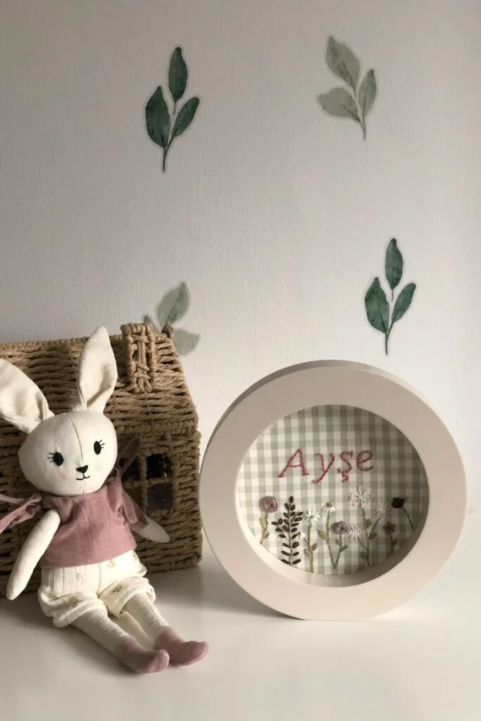 A bunny on a dresser in front of a wall decorated with leaf wall decals.