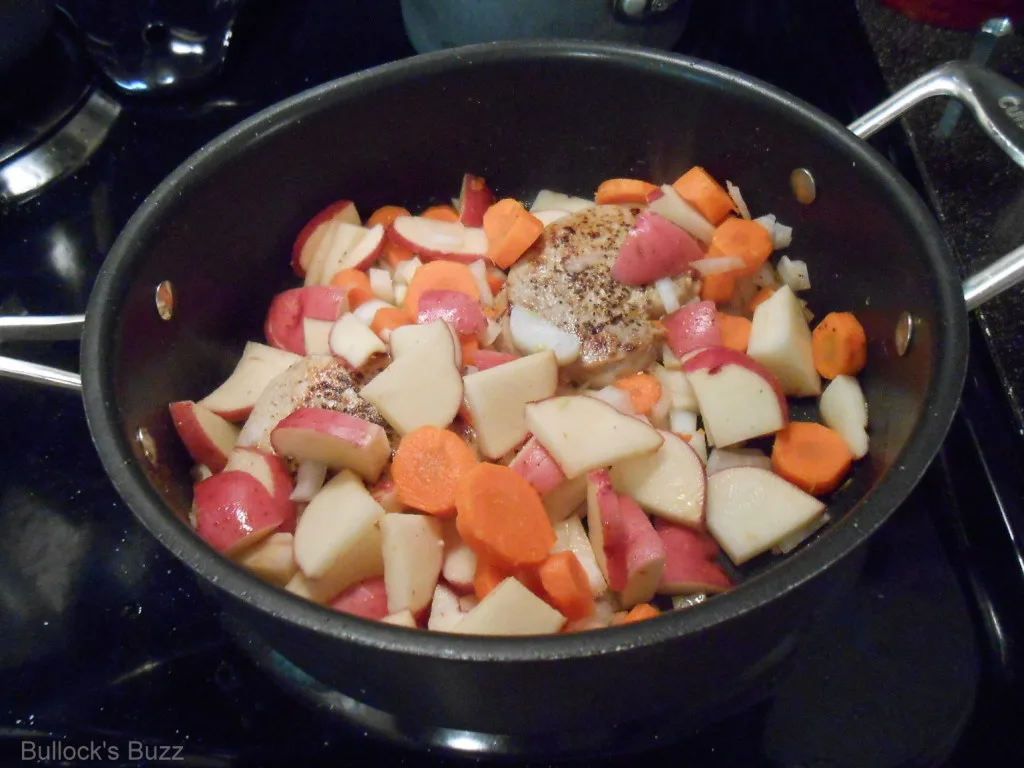 One Pot Pork Chop Dinner potatoes, onion and carrots in skillet