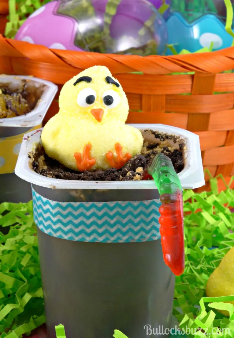 close up of an Easter Chick Pudding Cup with cookie dirt, a gummy worm and a yellow marshmallow chick.