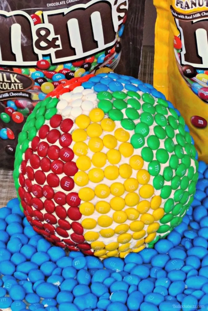 A Beach Ball Cake decorated with M&MS candy to look like a beach ball.