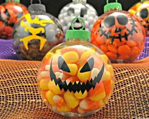 Several DIY Halloween candy ornaments displayed on orange and purple fabric.