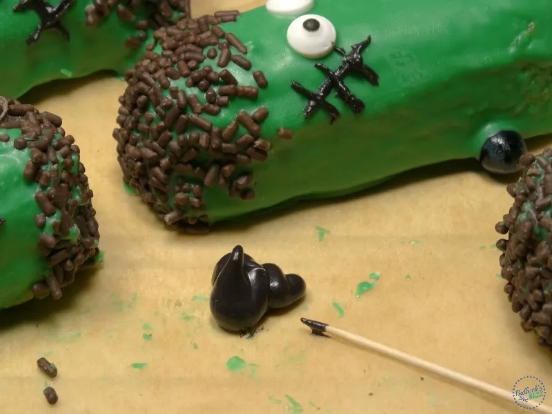 a pool of black icing with a toothpick next to it to make adding features to Frankenstein Twinkies easier