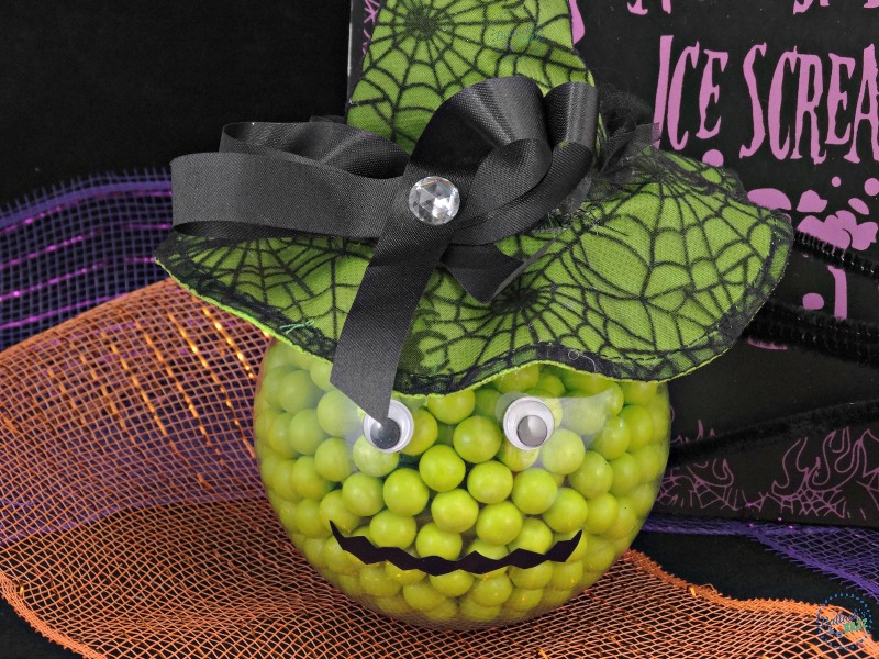 Ornament filled with green candies and decorated to look like a witch