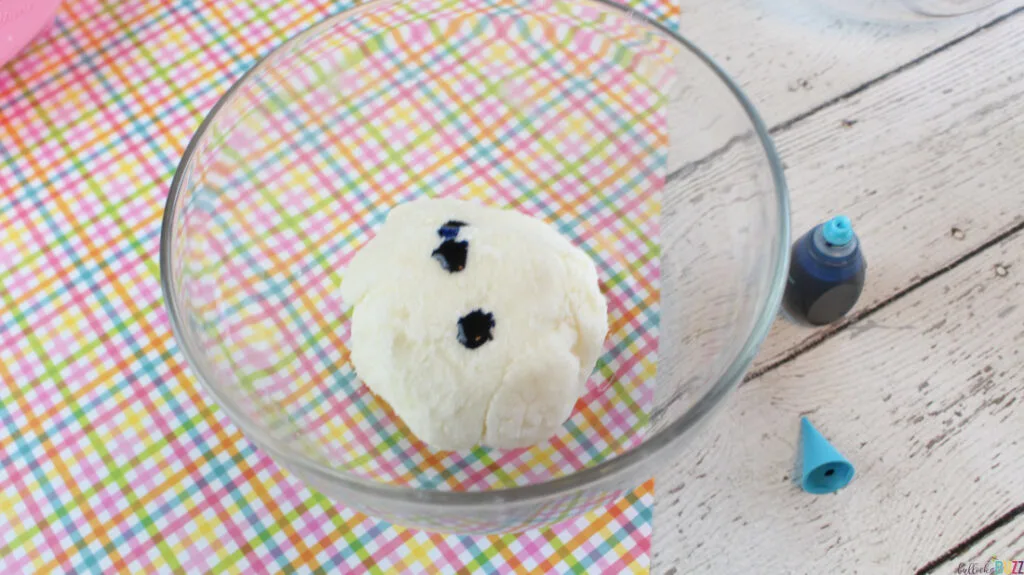 A section of cream cheese mints for Easter dough in a glass bowl with blue food coloring added before kneading to color the dough