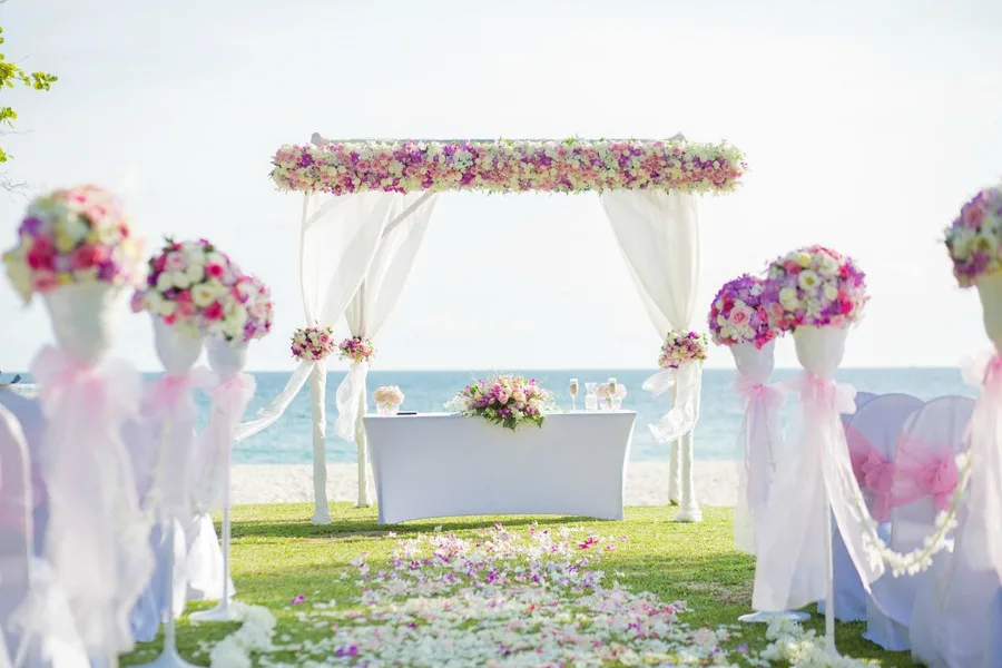 Wedding set up on a beach with pink and purple flowers. Choosing the right locale for your wedding can make or break your dream day 