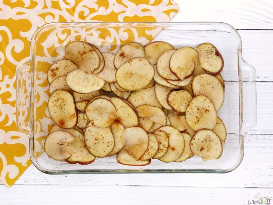 Thinly sliced and seasoned potatoes in baking dish to make oven roasted red potatoes