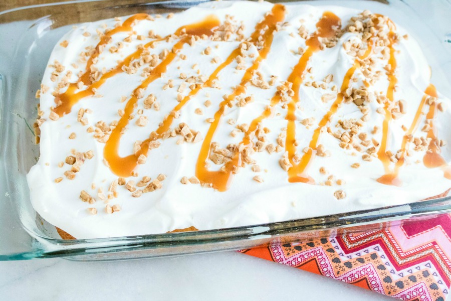 cover the caramel toffee poke cake with light frosting