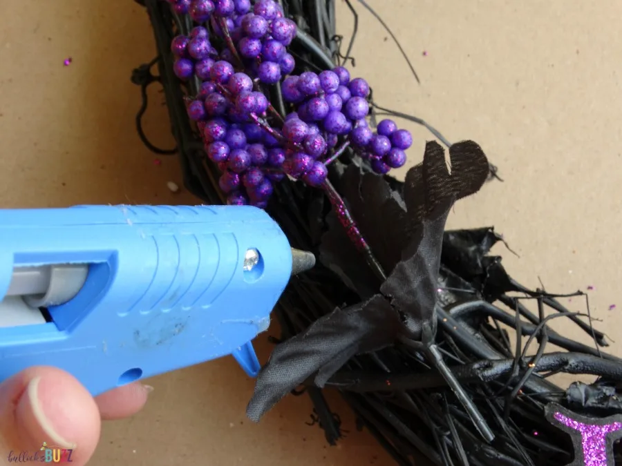 Use hot glue to attach accessories DIY Black and Purple Halloween Wreath