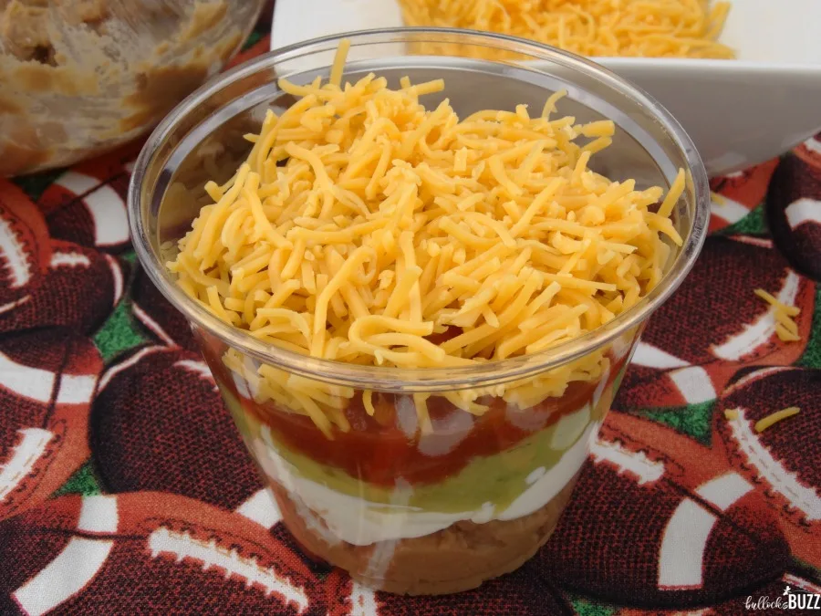 add the final layer of cheese to the Individual Five Layer Football Party Dip Cups