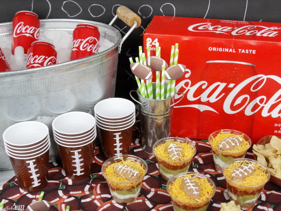 football party ideas Individual Five Layer Football Party Dip Cups on a table with football-themed cups and Cokes