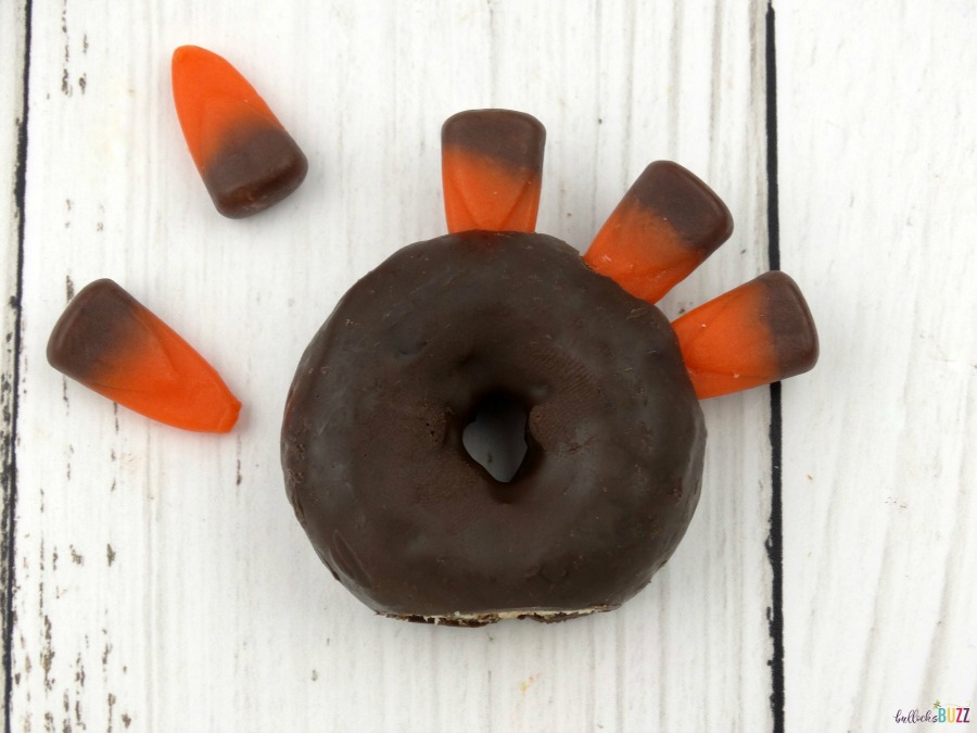 Carefully insert candy corn for the feathers on your mini donut turkeys treats for Thanksgiving.