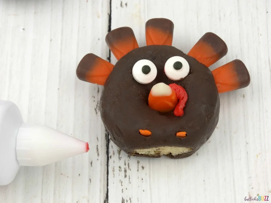 Use red icing add the snood to finish making these donut turkeys.