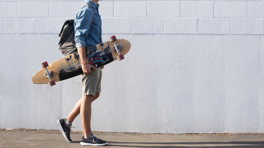 man carrying a longboard skateboard