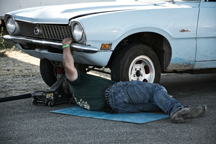 man working on car leaking fluid