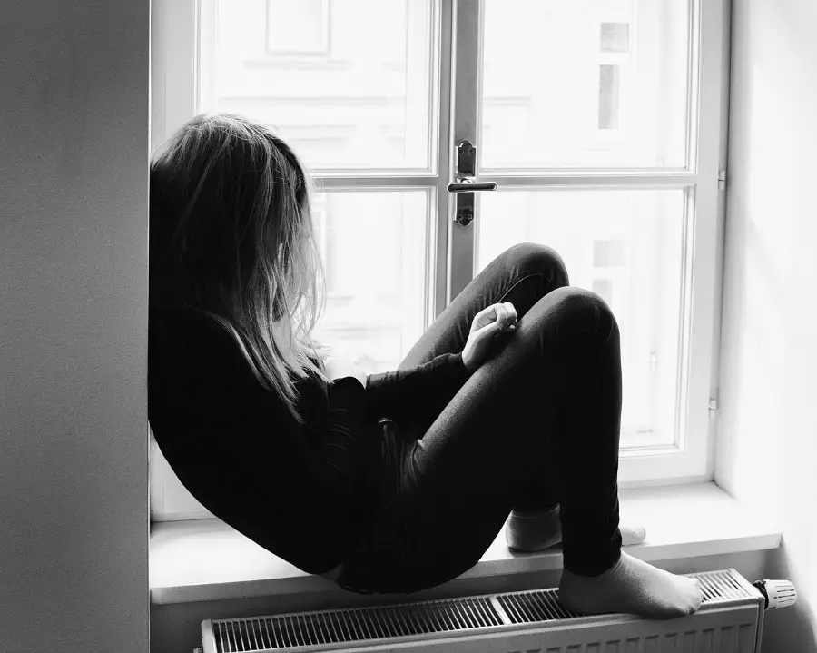 girl sitting in window suffering from teen depression