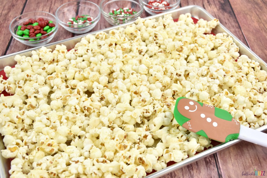 spreading the marshmallow-covered popcorn on a cookie sheet into a single layer