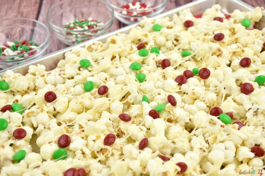Add red and green chocolate candies to the popcorn spread out on a baking sheet