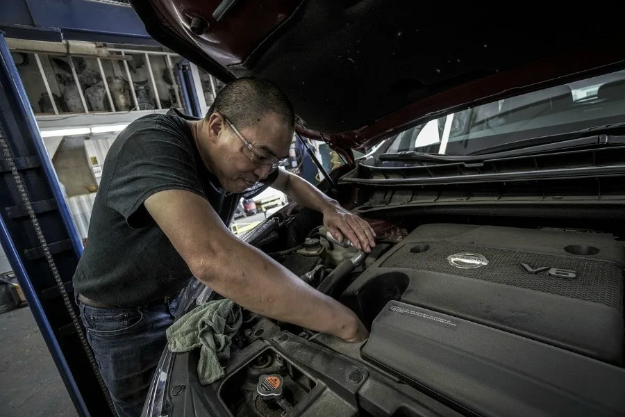 car mechanic working on car with Ultimate Car Maintenance Checklist