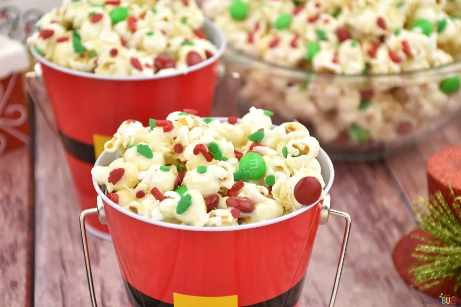 Close up image of finished Christmas popcorn in a Santa pail with a bowl full of the same popcorn in the background