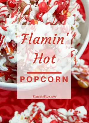 Close up of a bowl of Red Hot Valentine's Day Popcorn, featuring vibrant red meletd chocolate, red hot candies, and a sprinkling of Flamin' Hot Fries chips, creating a festive and tasty snack perfect for the holiday.