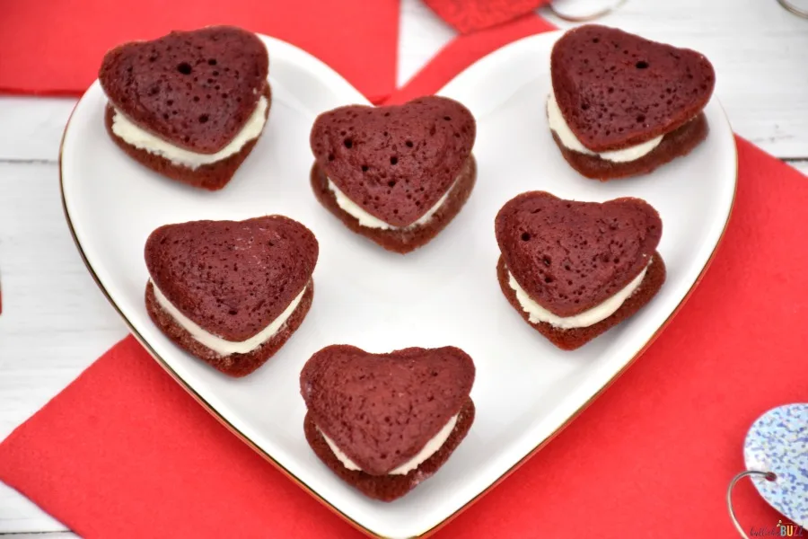 Finished mini heart-shaped red velvet whoopie pies on a white heart shaped serving plate