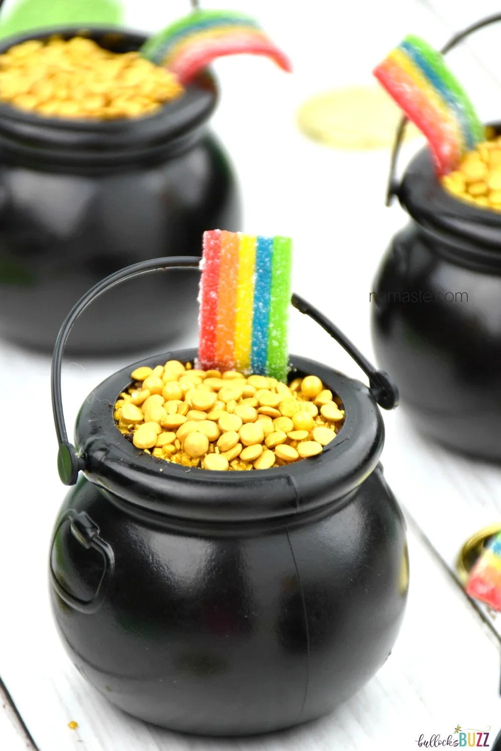 Layers of rich, chocolatey cookies and creamy chocolate pudding, topped with gold sprinkles, and sour rainbow candy make these St. Patrick's Day Pot of Gold Dirt Cups taste as good as they look! #recipes #StPatricksDay #bullocksbuzz