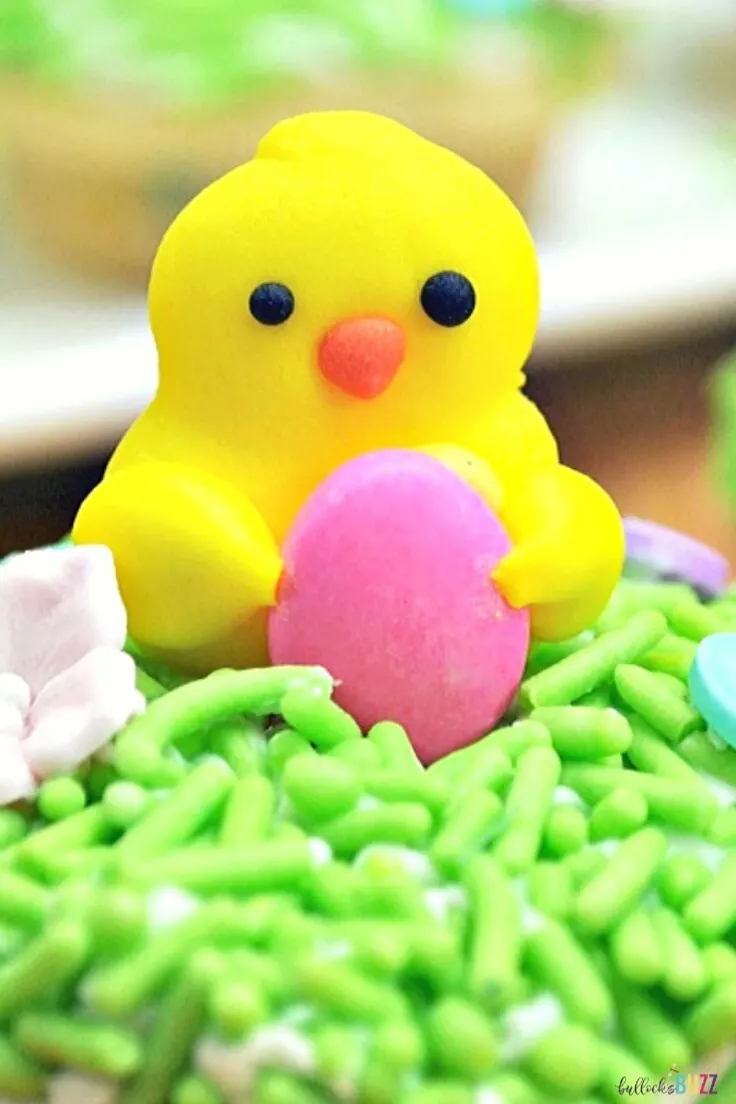 Close up of candy chicks holding an easter egg on top of cookie cuos