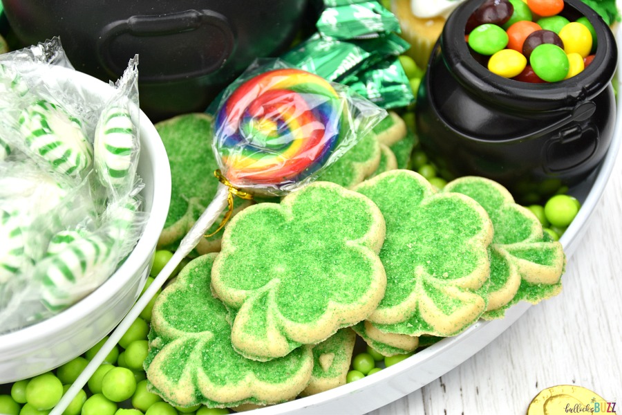 shamrock cookies and rainbow lollipops on this dessert board