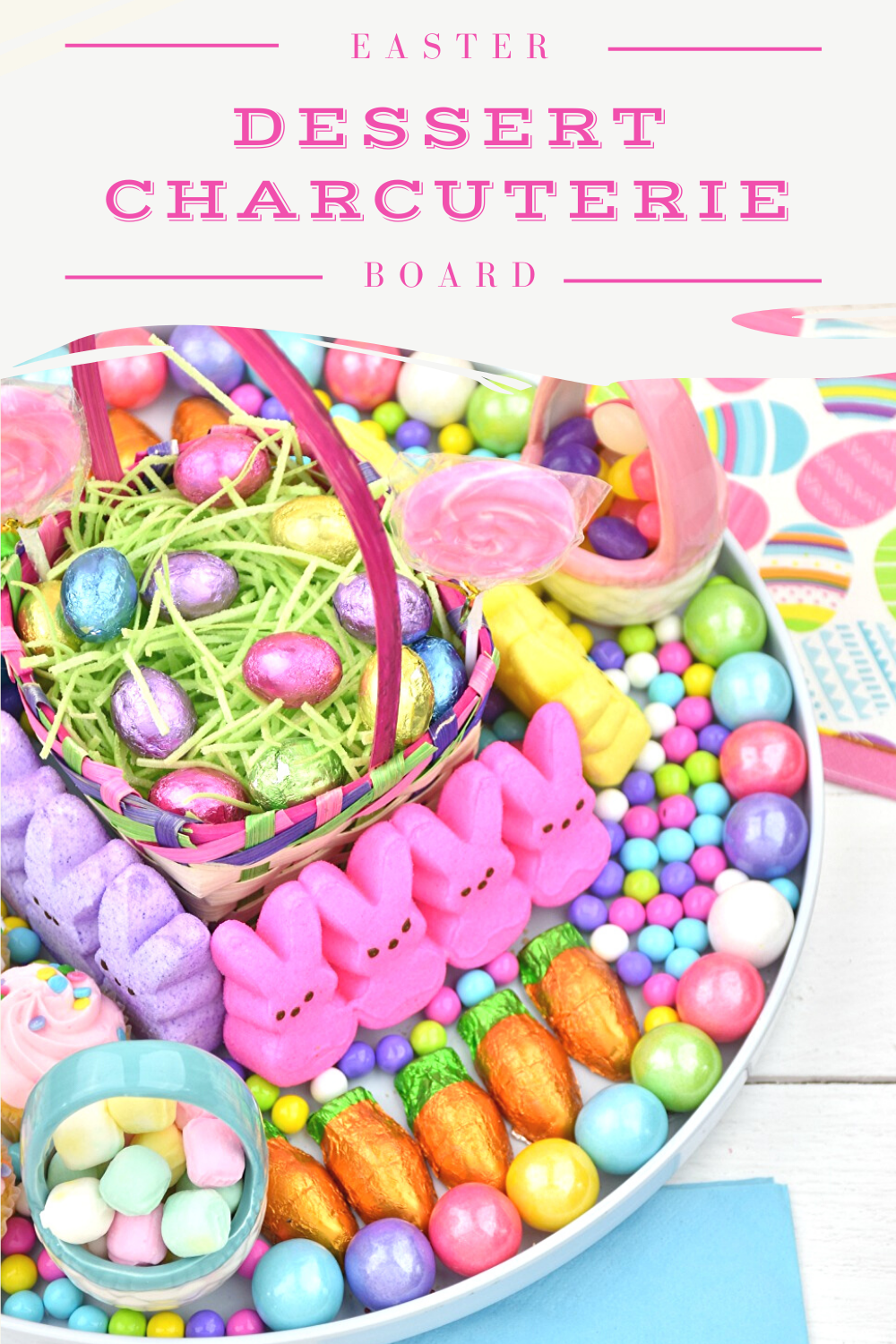 An overhead image of the Easter Dessert Charcuterie Board filled with pastel-colored and Easter-themed candy and sweets all surrounding a small Easter basket filled with edible grass and chocolate Easter eggs.