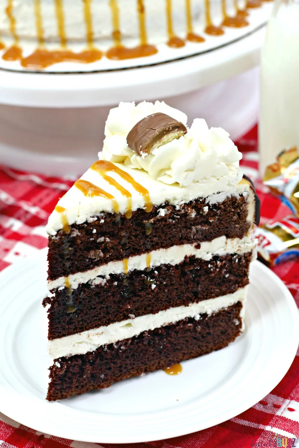 Rich, chocolate cake and buttery caramel frosting is topped off with drizzles of caramel and chocolate syrup and crowned with bite-sized pieces of Twix candy bars in this best-ever Twix cake recipe! #cakes #recipe #TwixCake