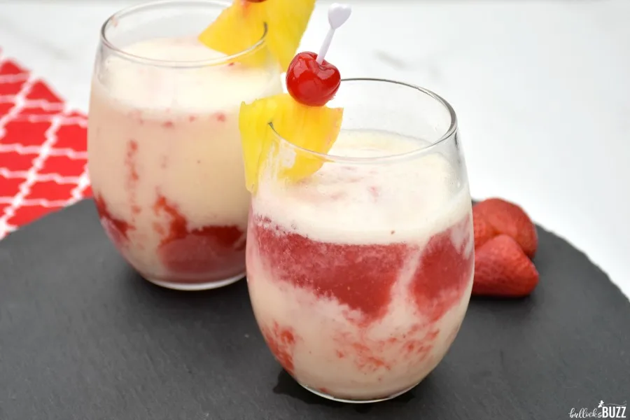 red and white cocktail garnished with a cherry and a slice of pineapple