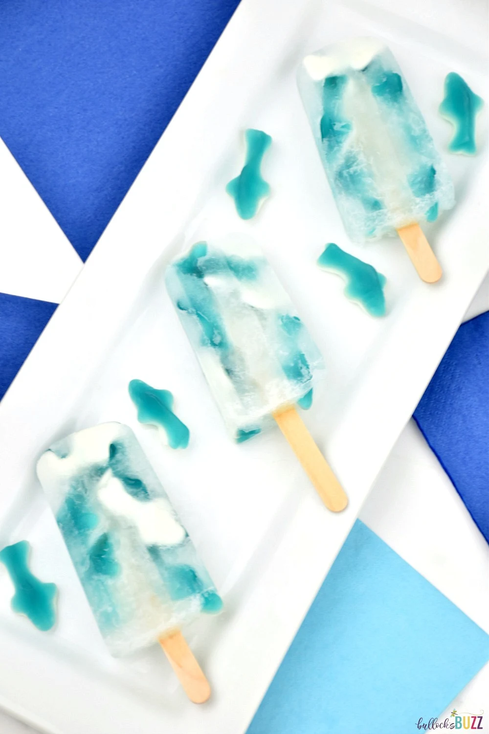Perfect for Shark Week or an ocean themed party, fruit flavored gummy sharks are submerged in lemon-lime soda and frozen in this tasty Great White Gummy Shark Popsicle recipe.
