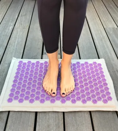 woman standing on purple Dosha mat accupressure