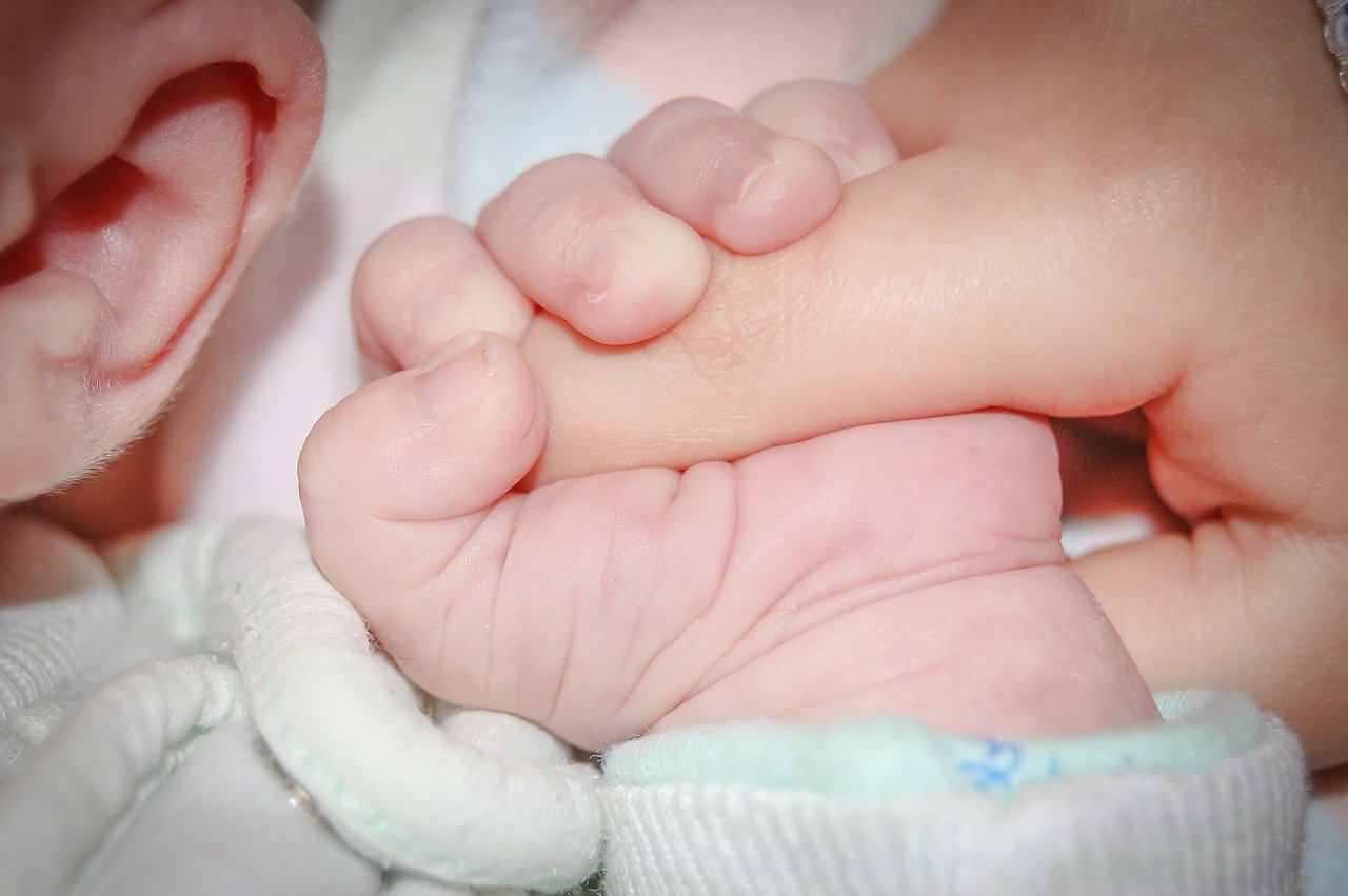 baby from frozen donor eggs holding parent's thumb