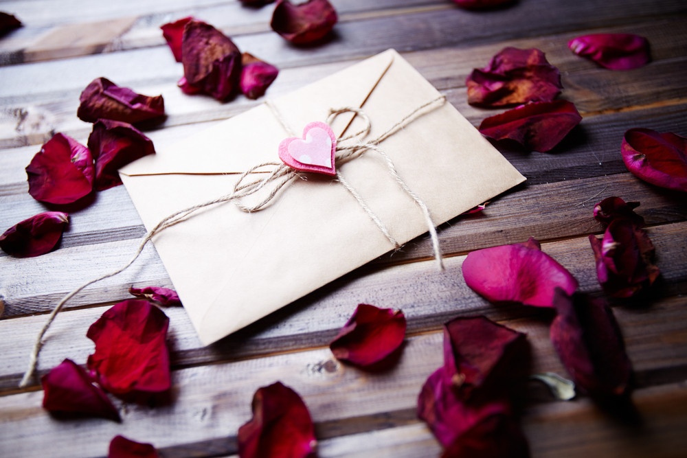 love letter with small pink heart surrounded by rose petals