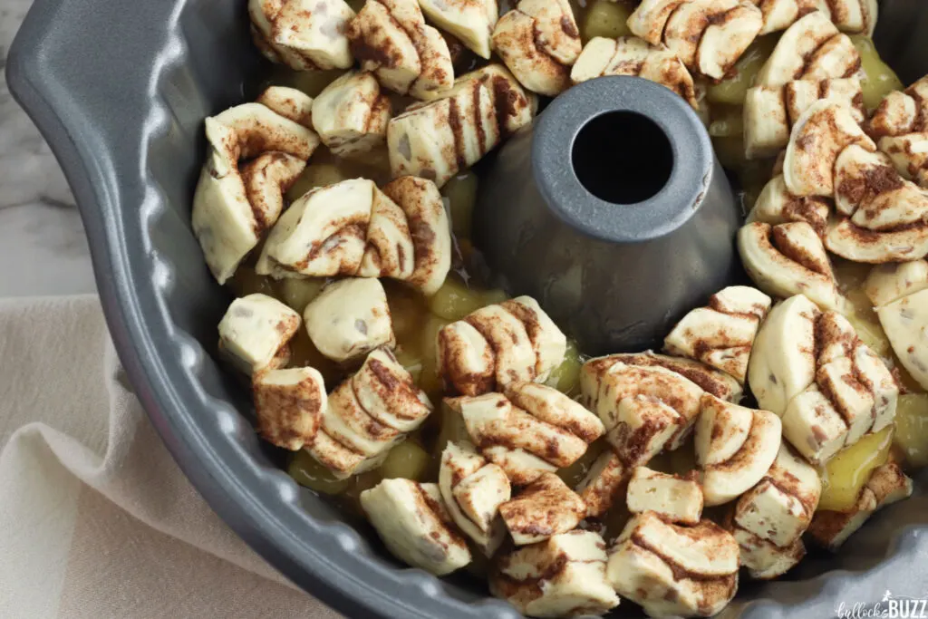 layers of cinnamon rolls and apple pie filling in bundt cake pan for cinnamon apple monkey bread recipe