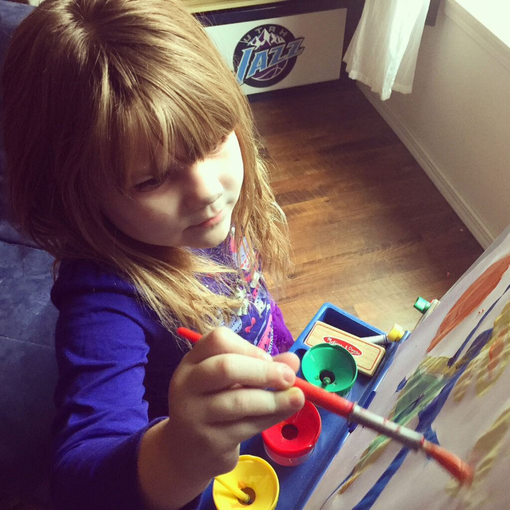 young child painting in a school that uses The Montessori method of education.