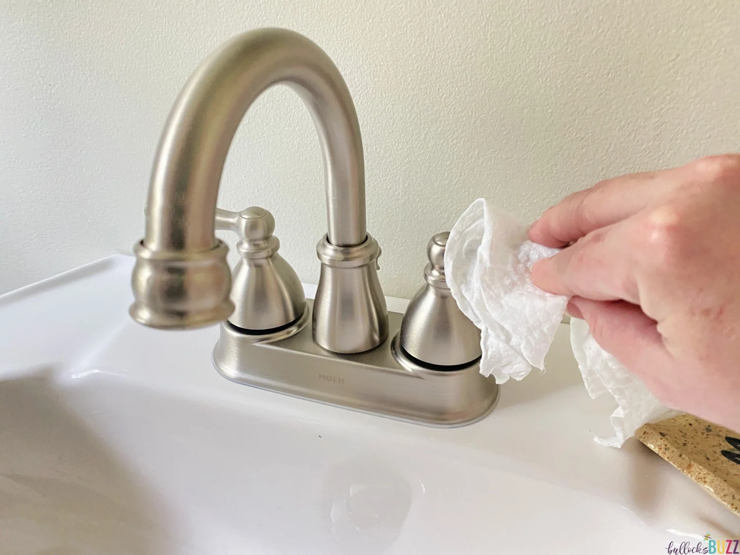 cleaning faucet with Arm and Hammer Essentials Disinfecting Wipes as part of weekly cleaning schedule