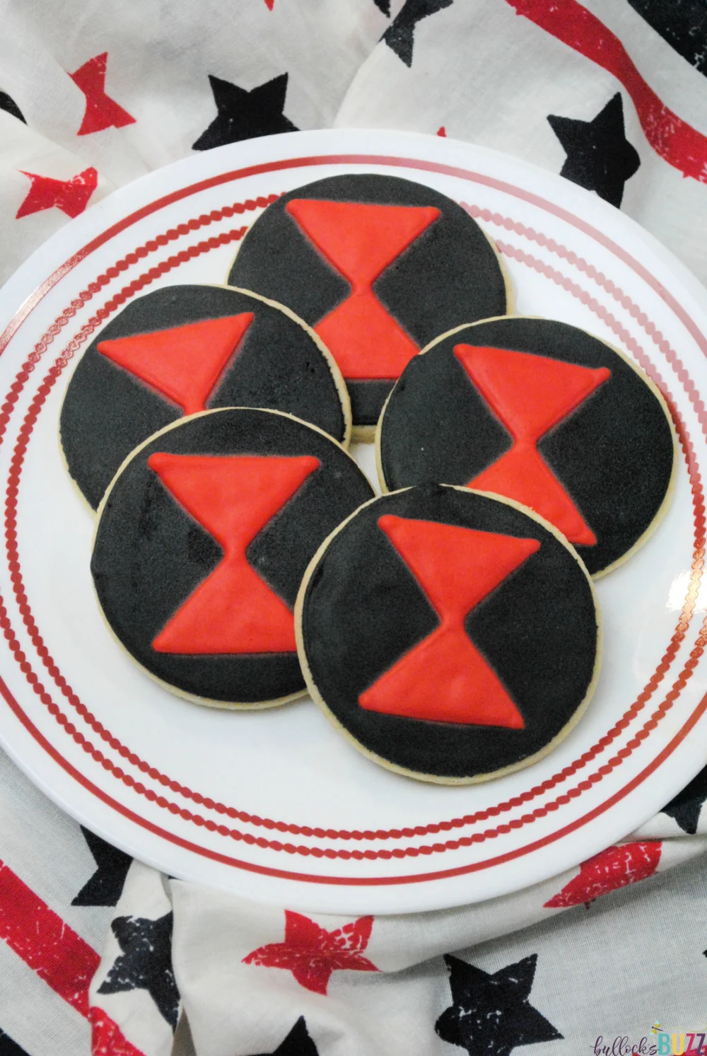 Five Avengers Black Widow Cookies on white plate with red trim.
