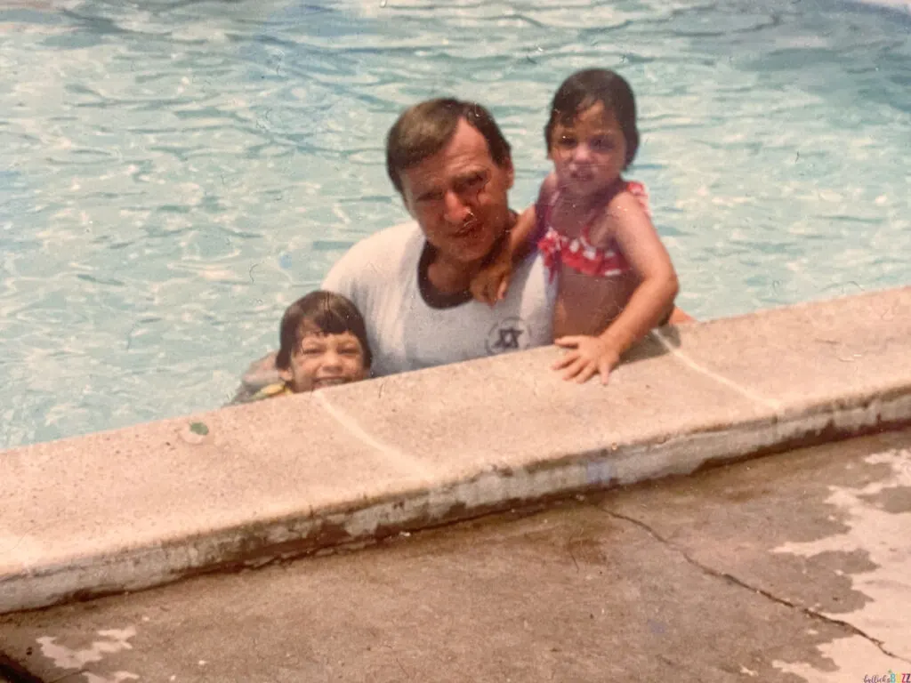 An old picture of my dad, sister and me swimming in a pool when we were little kids.