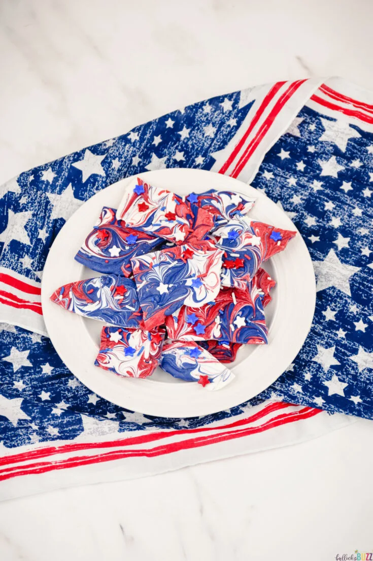 Making this red, white, and blue candy bark is as easy as melting the candy melts, swirling them together, and then adding the sprinkles. Then you let it sit until it’s ready to eat. #4thofJuly #candybark #candy #recipe #candyrecipe