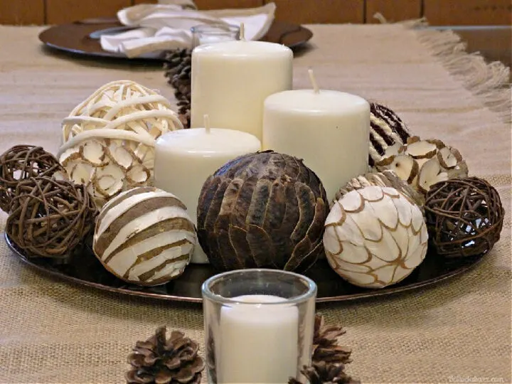 candles surrounded by wicker balls on a charger for a  DIY THANKSGIVING CENTERPIECE NEUTRAL CANDLE GROUPING