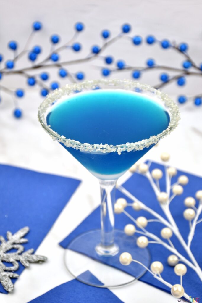 pretty blue cocktail in martini glass sitting on blue napkins
