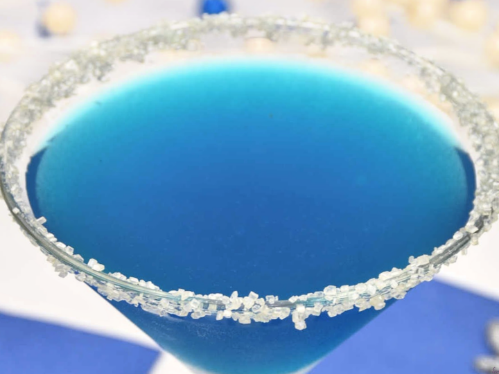 close up of Blue Glacier holiday cocktail in glass rimmed with white sugar