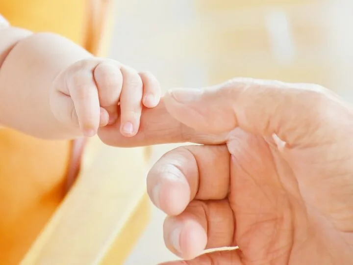 baby holding dad's finger