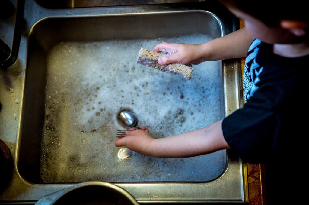 child helping wash the dishes