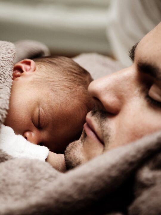 man with sleeping baby on his chest during paternity leave