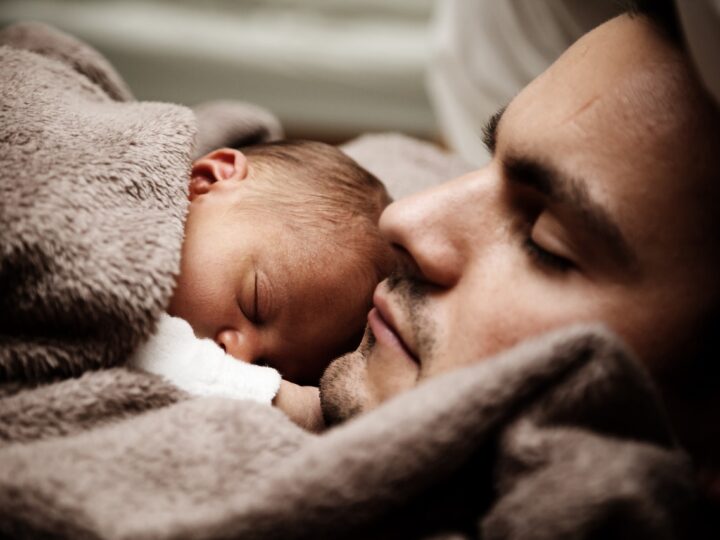 man with sleeping baby on his chest during paternity leave