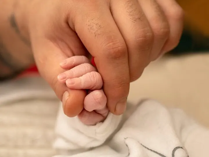 man holding baby's hand in his